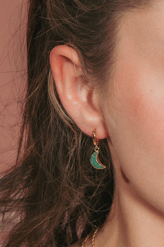 Model wearing green gemstone crescent moon huggie hoop earring.