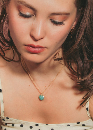 A woman with brown hair wearing a amazonite heart charm necklace.