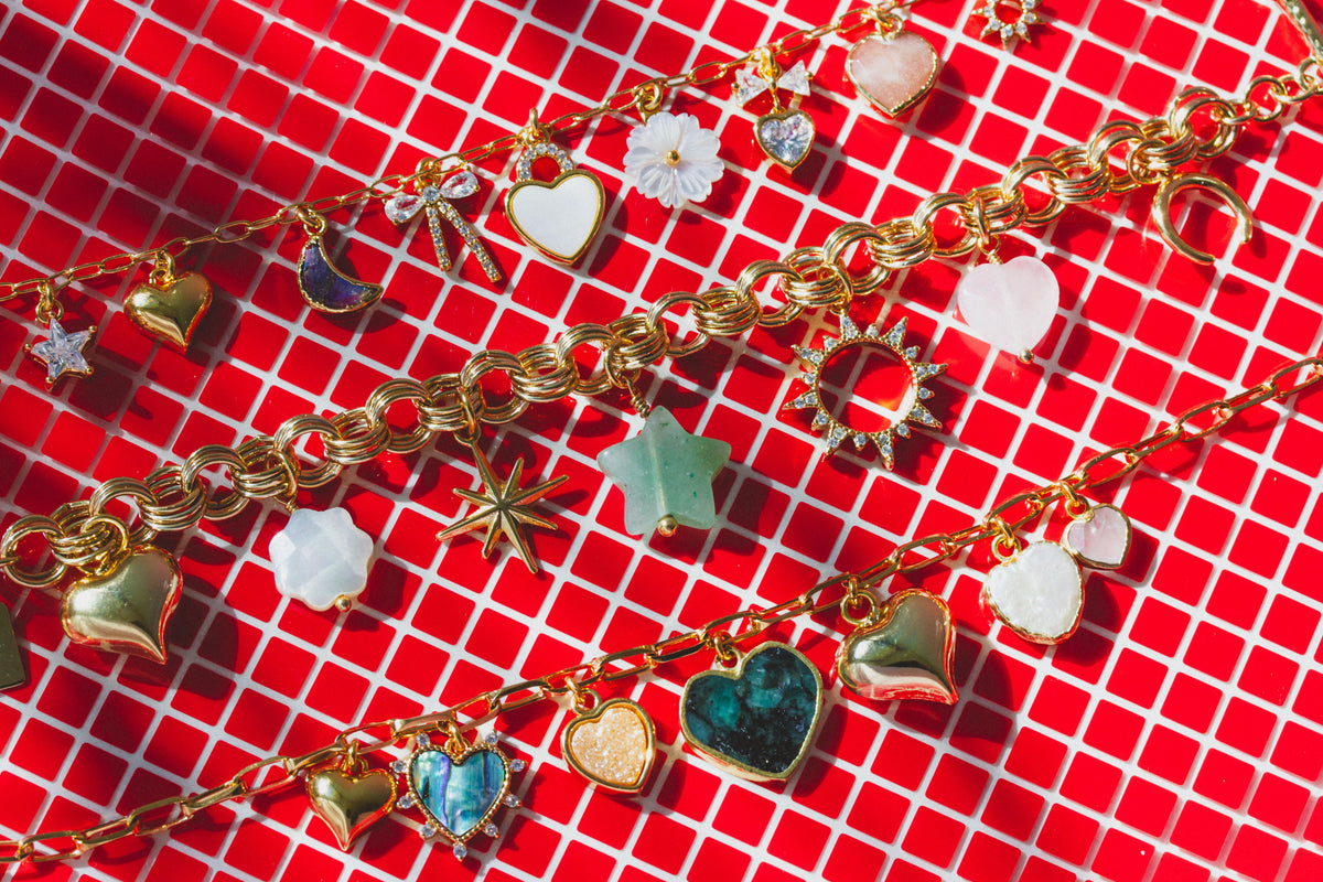 Three necklaces, each with many gemstone charms on a red and white checkered background.