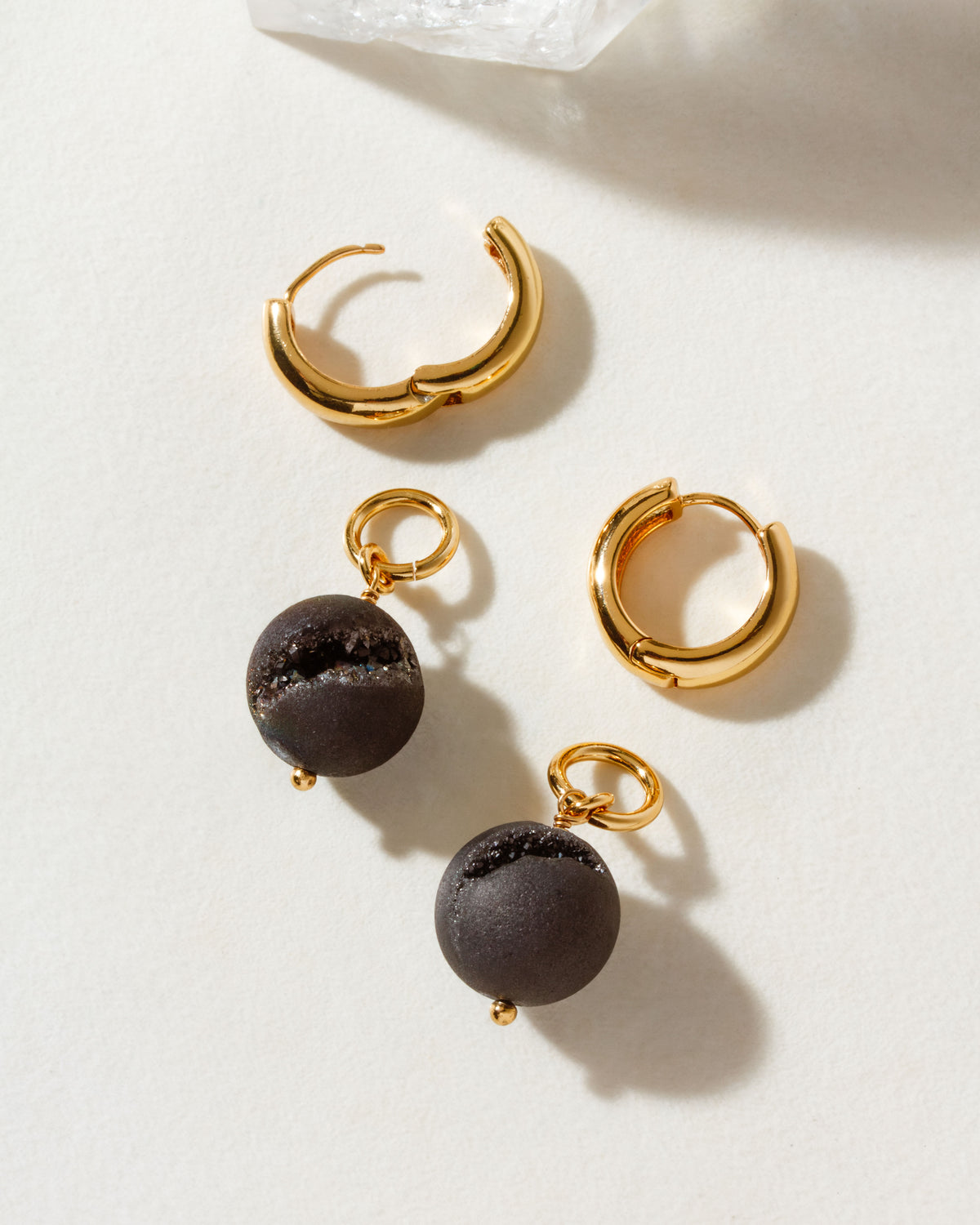 Gold hoops, one with a dark druzy sphere charm