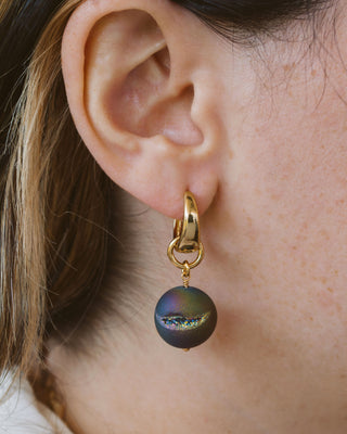 Closeup of person wearing gold rainbow druzy sphere hoop earring.