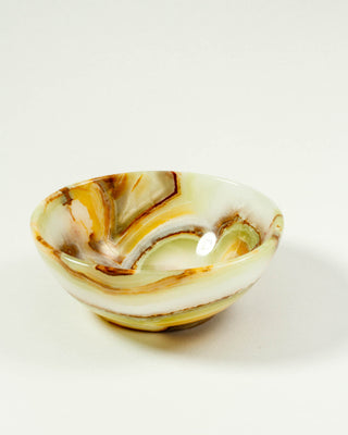 A banded calcite jewelry bowl, displaying earthy tones like greens, browns, and beige.