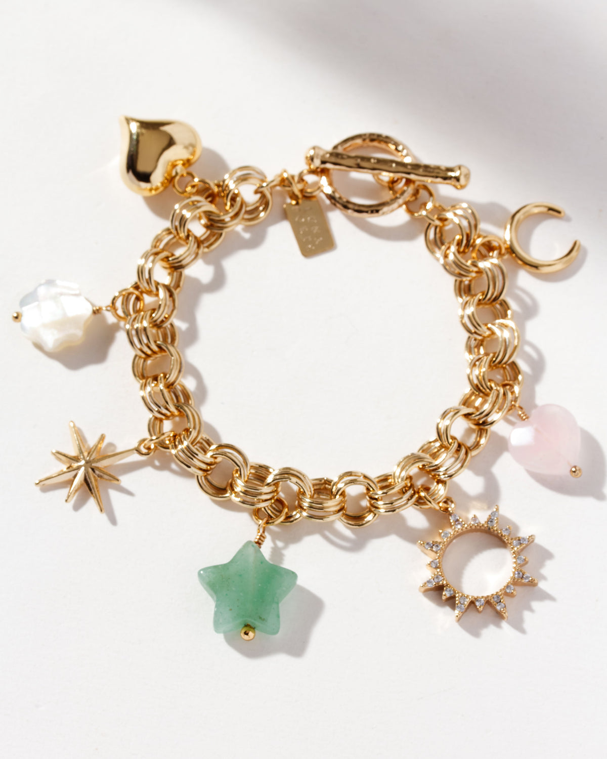 Gold-plated charm bracelet with charms with a heart, a flower, a star, and gem beads.