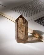 Brown quartz crystal on an open book with a soft focus background