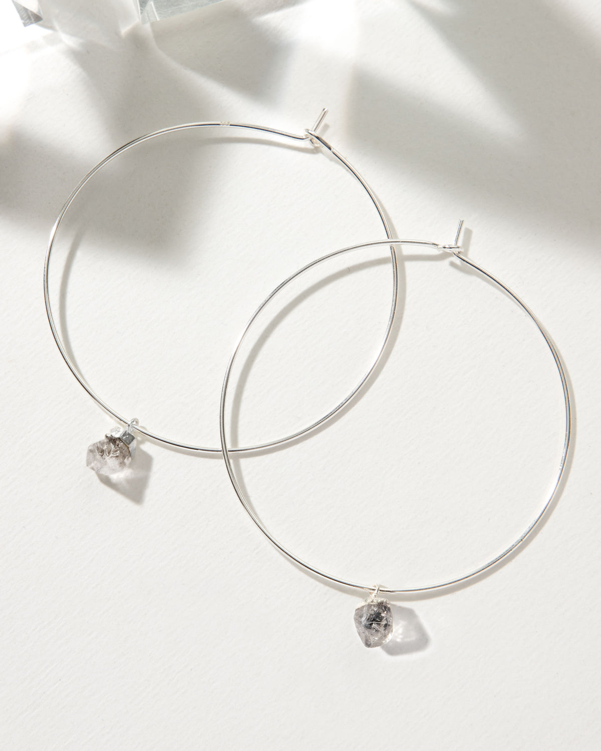 Two Keep It Casual hoop earrings in sterling silver are displayed on a white surface.