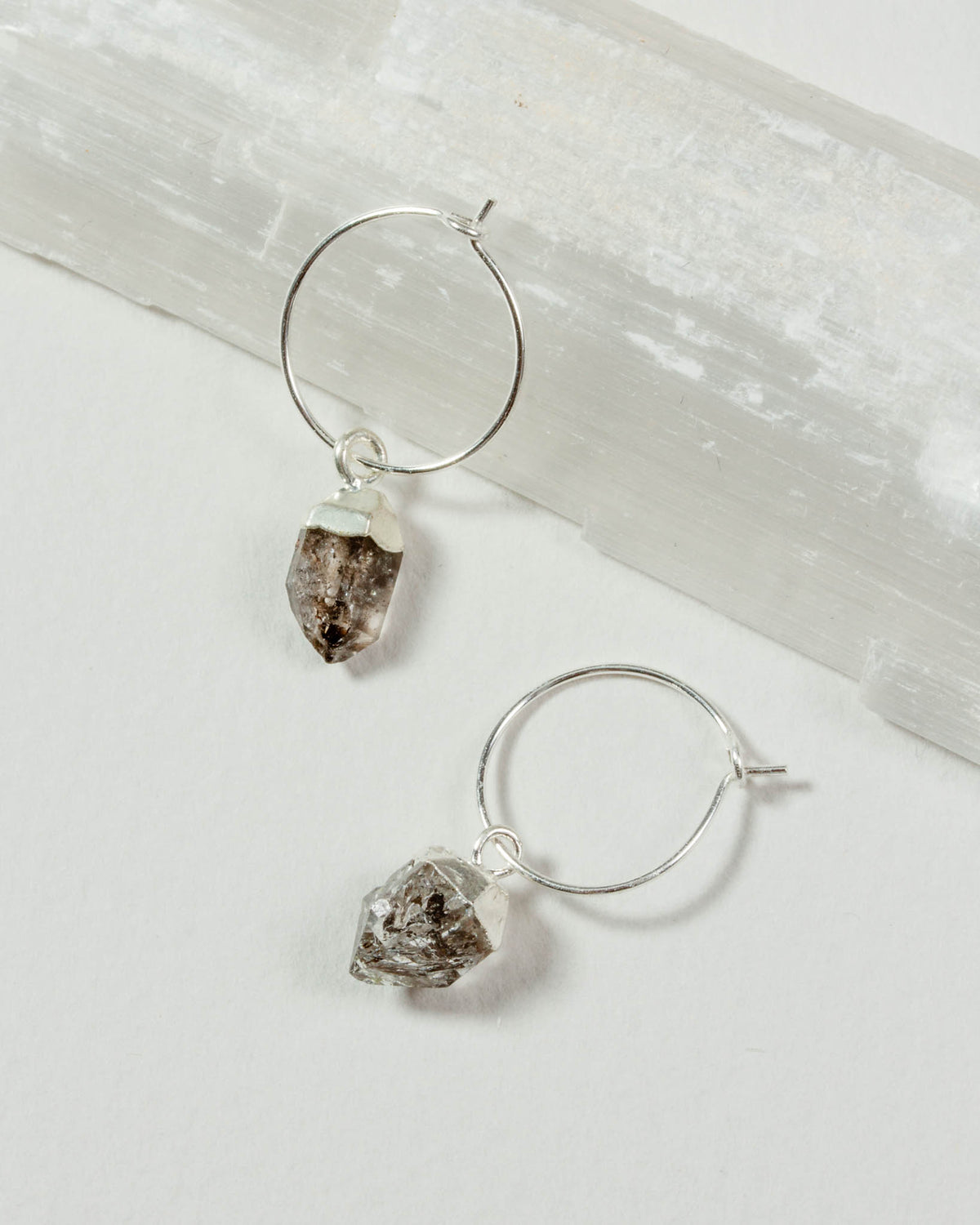 Sterling silver hoop earrings with raw, irregular clear Herkimer quartz gemstone dangles.