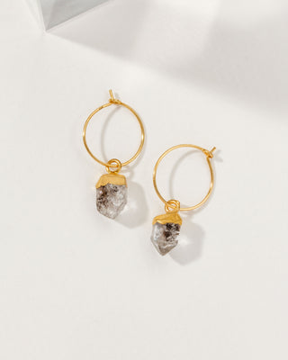 Gold hoop earrings with natural rough herkimer quartz stone drops on a white background