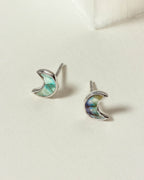 Pair of silver labradorite crescent moon shaped charm earrings on a white surface.