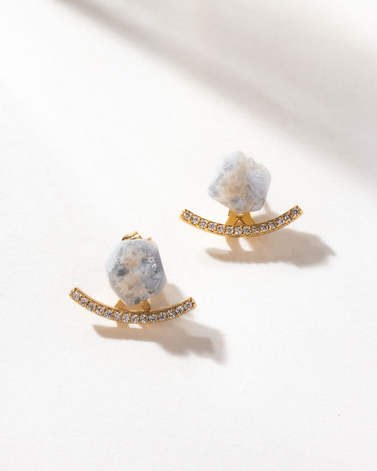 Druzy quartz post earrings with CZ pavé jackets on a white surface.