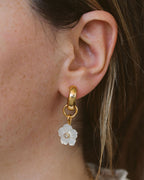 Closeup of woman wearing mother of pearl floral interchangeable huggie hoop earring.