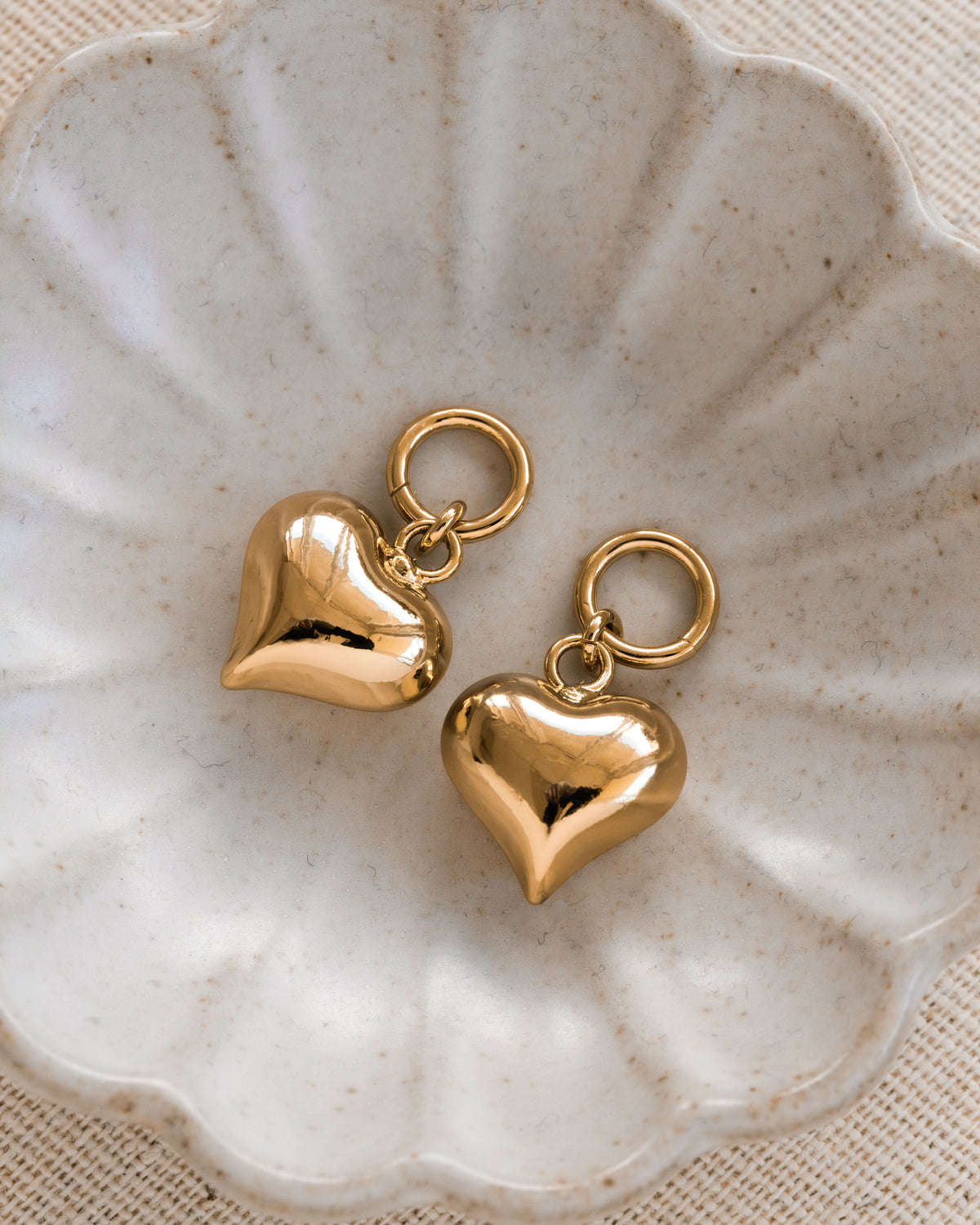 Two gold heart-shaped earring charms with small hoop attachments