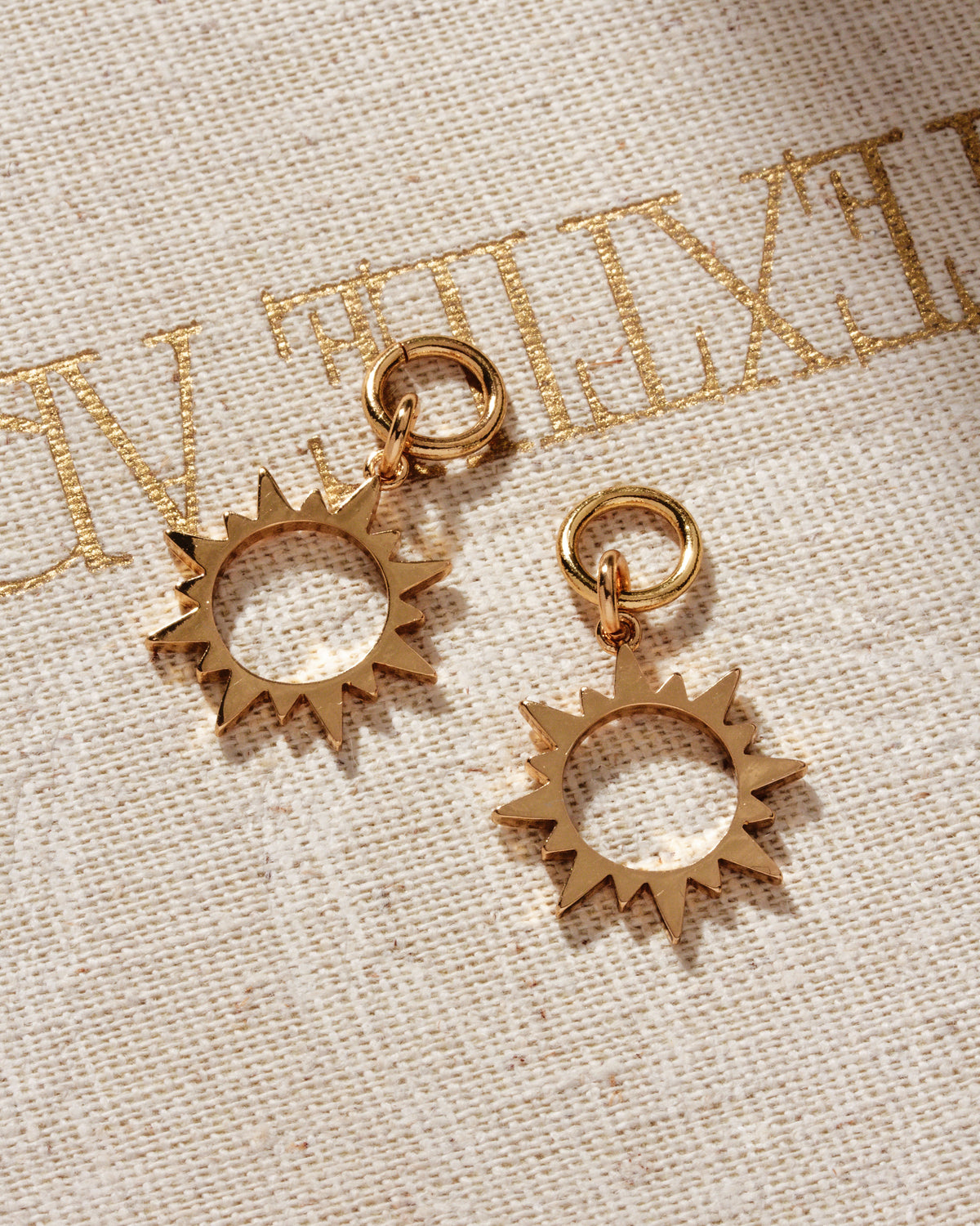 Two gold hoop earring sun charms designed to resemble coffee beans