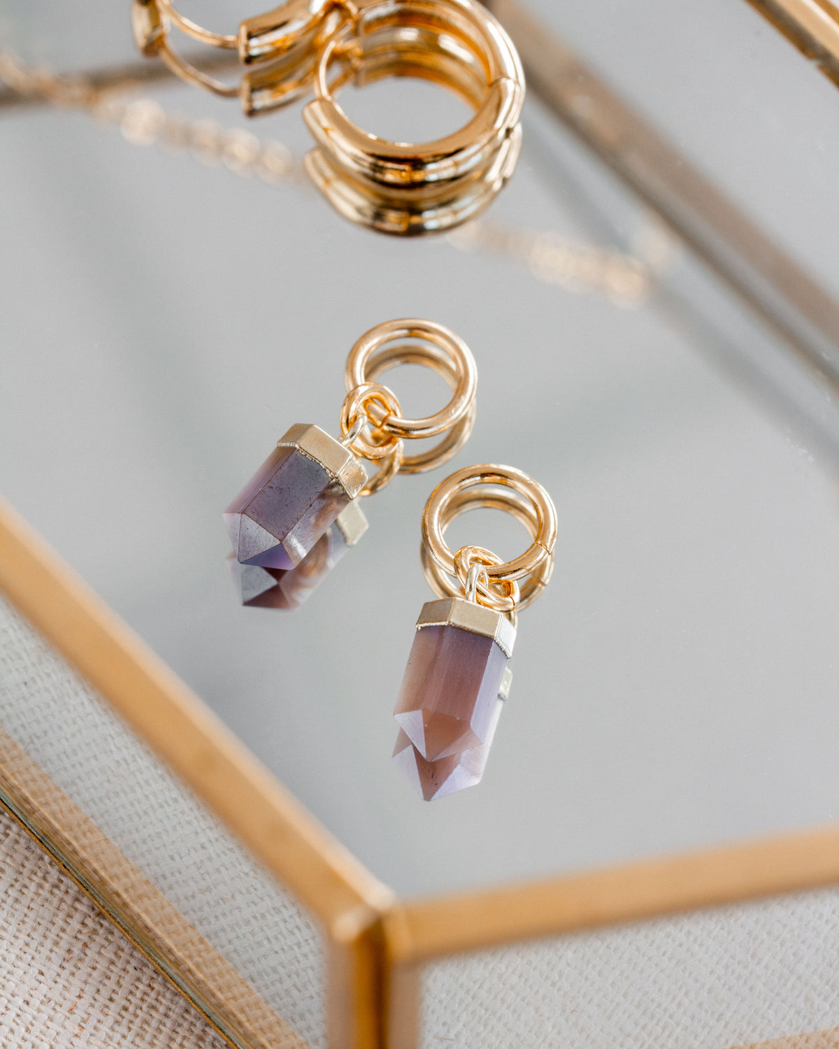 Interchangeable hoop earring charms with coffee moonstone gemstones attached to gold hoops