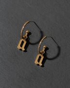 Gold hoop earrings with letter 'a' charms on a dark gray background