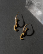 Gold earrings with letter 'C' design on a dark surface
