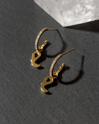 Gold earrings with a letter 'e' on a dark surface