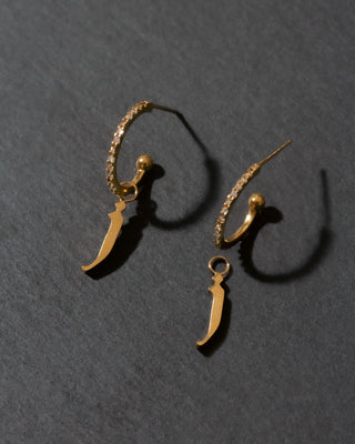 Gold letter 'j' earrings on a dark gray background