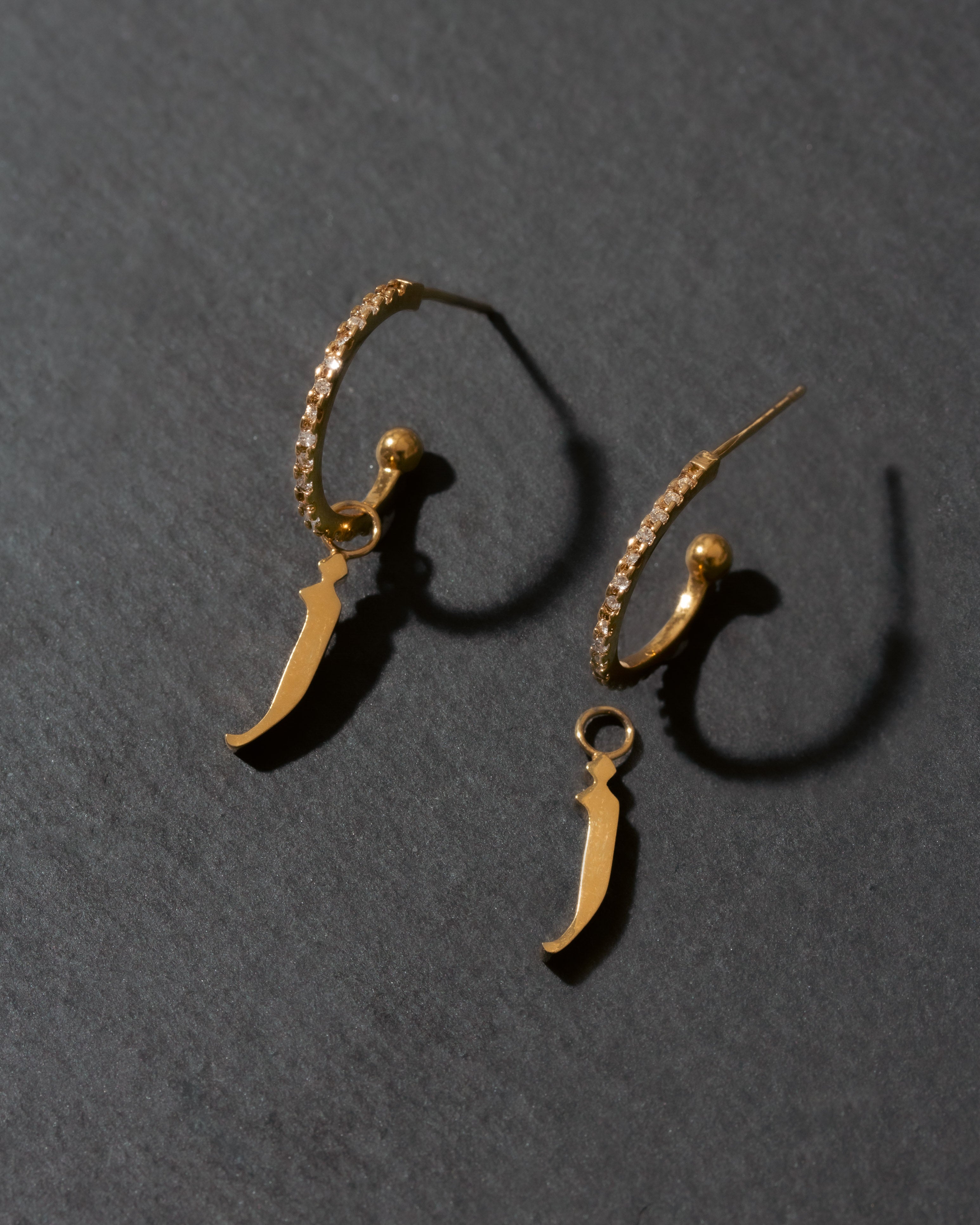 Gold letter 'j' earrings on a dark gray background