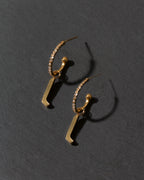 Gold letter 'l' earrings on a dark gray background