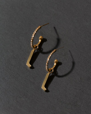Gold letter 'l' earrings on a dark gray background