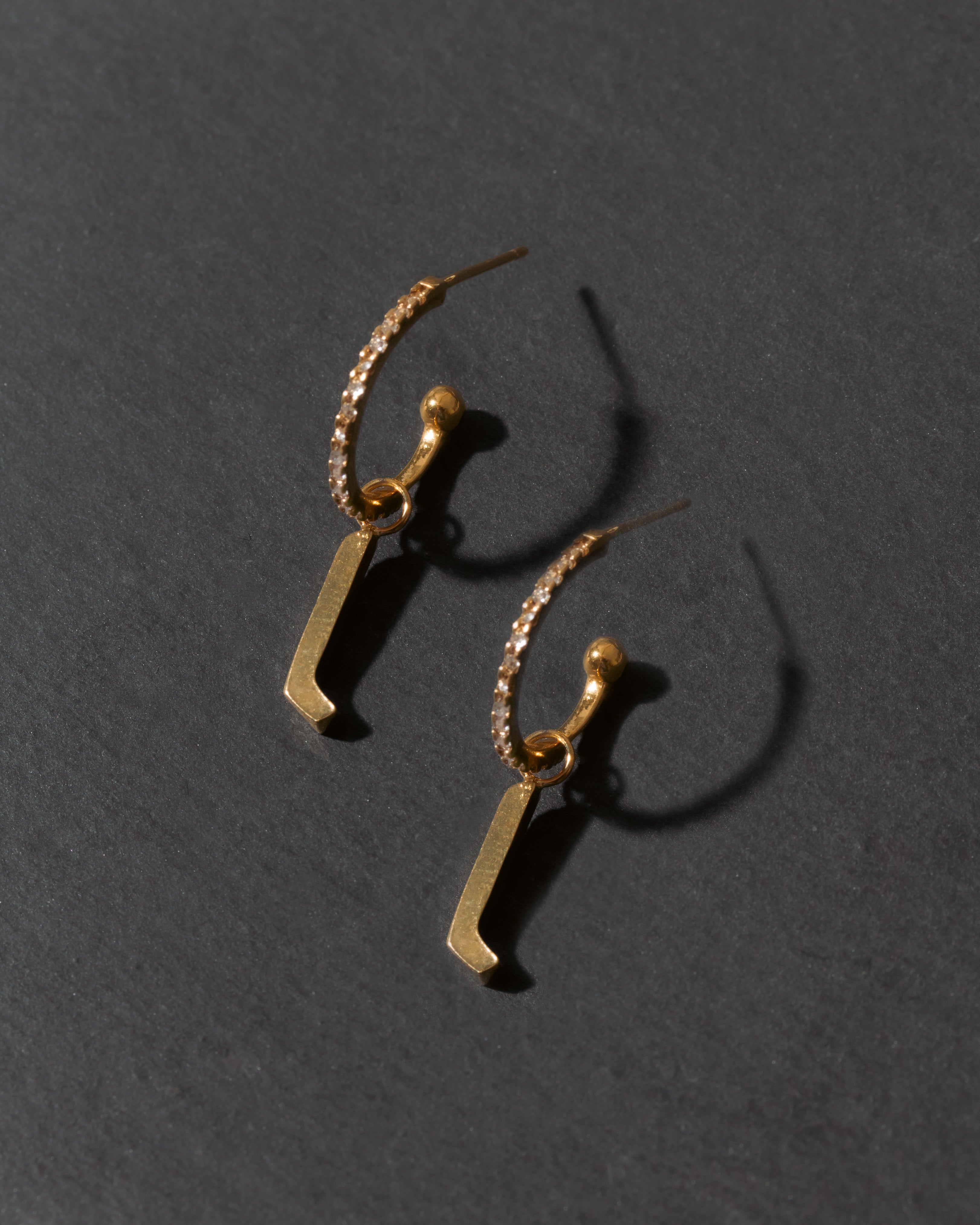 Gold letter 'l' earrings on a dark gray background