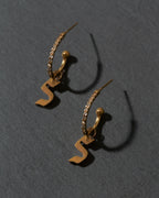 Gold earrings with 'S' initials on a gray background