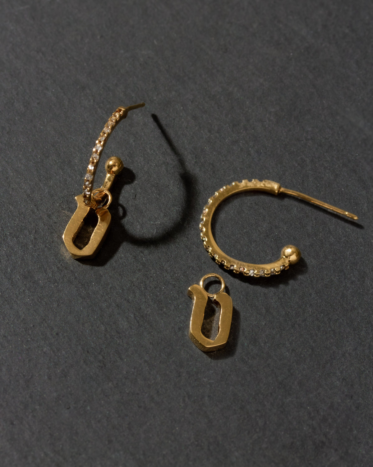 Gold earrings with letter 'v'on a dark gray background