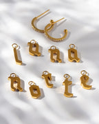 Gold cz earrings pair above many letter-shaped charms spelling out "luna norte." 