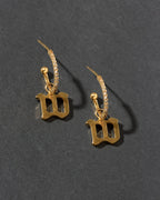 Gold earrings with 'W' charm on a dark gray background