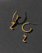 Gold hoop earrings with letter 'Z' charms on a dark gray background