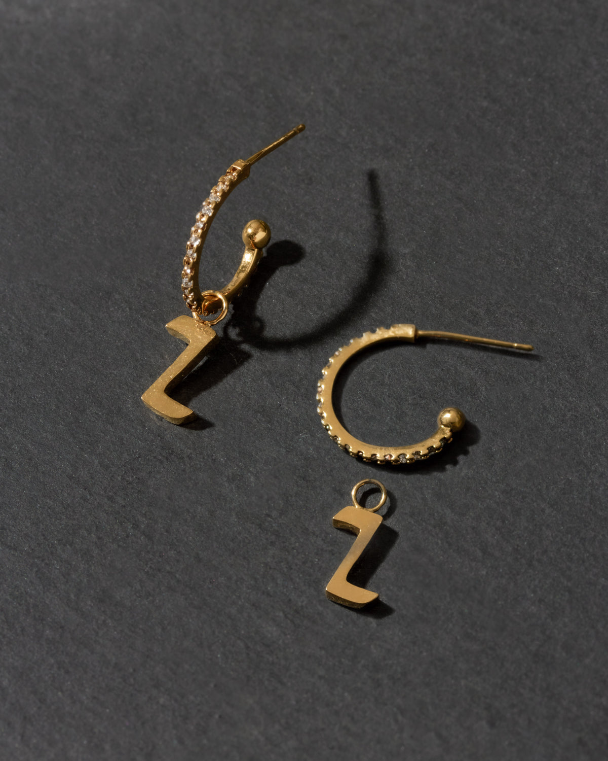 Gold hoop earrings with letter 'Z' charms on a dark gray background