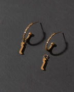 Pair of gold letter "i" earrings on a dark gray background