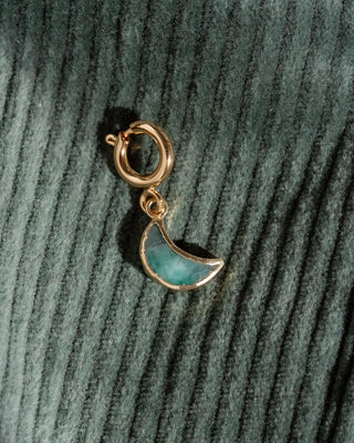 Gold aand green moon charm on a textured green background