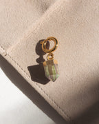Gold c-clasp charm with a multicolor crystal on a beige surface