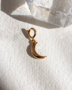 Gold crescent moon charm on a white surface background