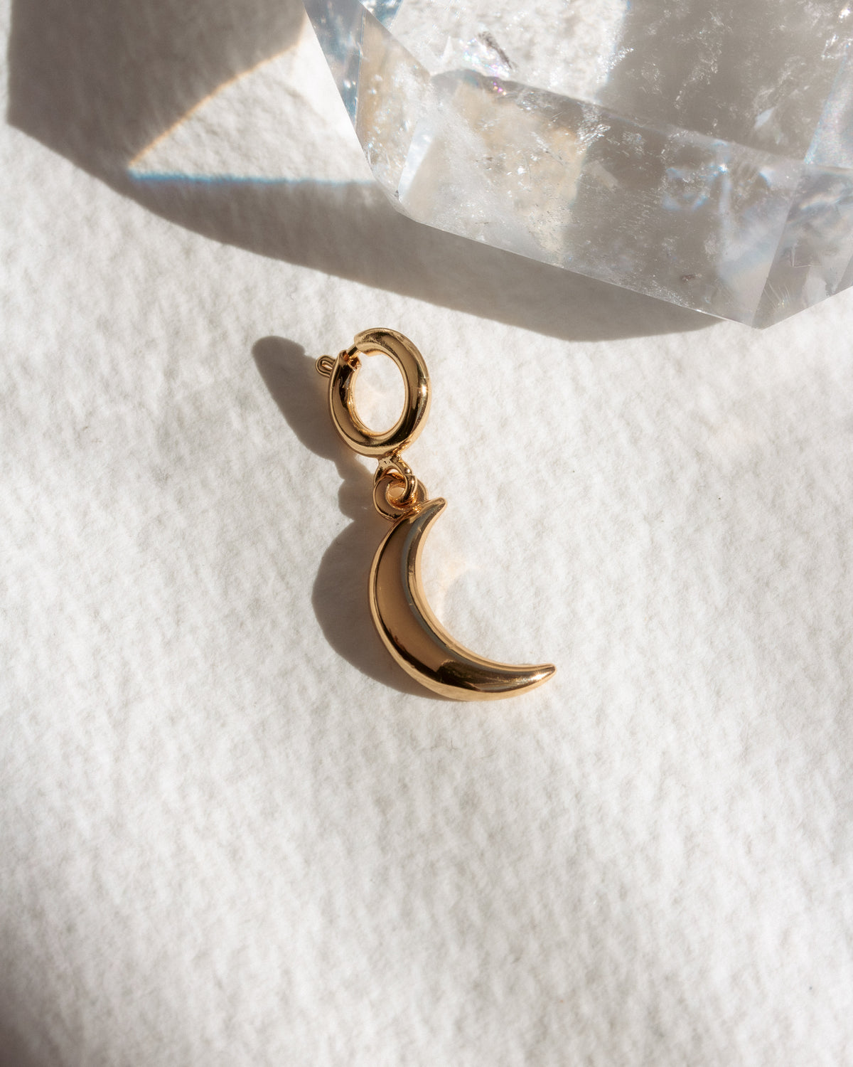 Gold crescent moon charm on a white surface background