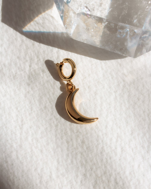 Gold crescent moon charm on a white surface background
