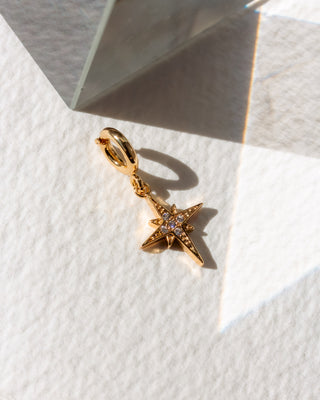 Gold star-shaped cz charm on a textured white surface