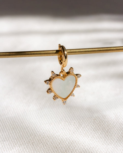 Gold heart-shaped pendant with a white center on a white background
