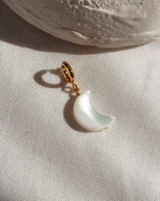 Crescent moon-shaped charm with gold c-clasp on a neutral background