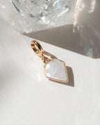 Gold charm with a geometric design on a white surface