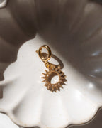 Gold sun-shaped charm on a white background