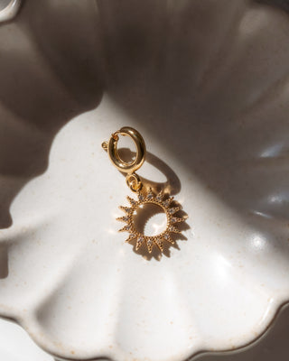 Gold sun-shaped charm on a white background