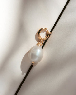 Pearl charm with gold clasp against a white background