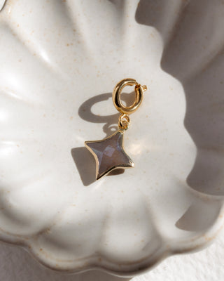 Gold charm with a star-shaped pendant on a white background