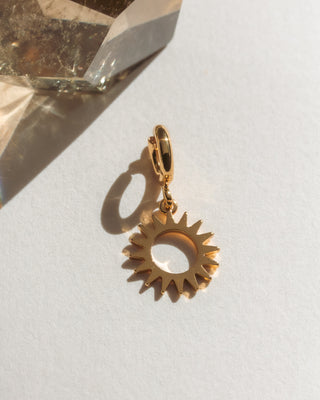 Gold sun-shaped pendant on a light background