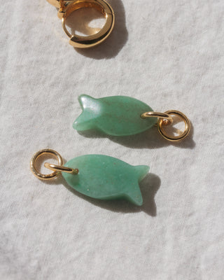 Two green fish-shaped charms with gold loops on a light gray background