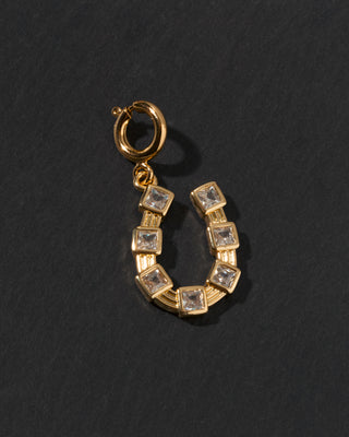 Gold c-clasp horseshoe charm with clear CZ embedded stones on a dark background