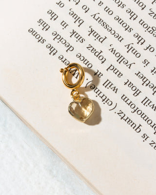 A gold heart-shaped citrine charm with a loop at the top.