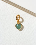 A small gold heart-shaped charm with a faceted green aventurine stone, attached to a gold c-clasp.